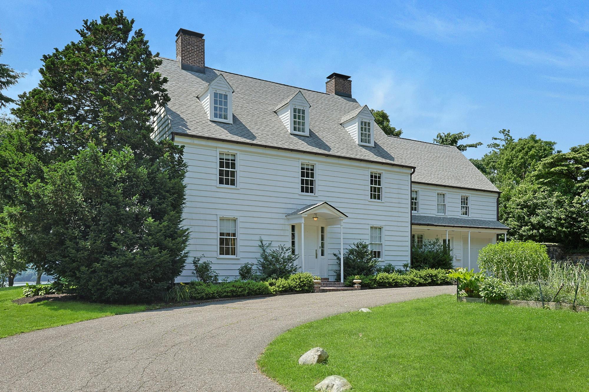 Front elevation from the circular drive — classic colonial façade with three dormers and twin chimneys.
