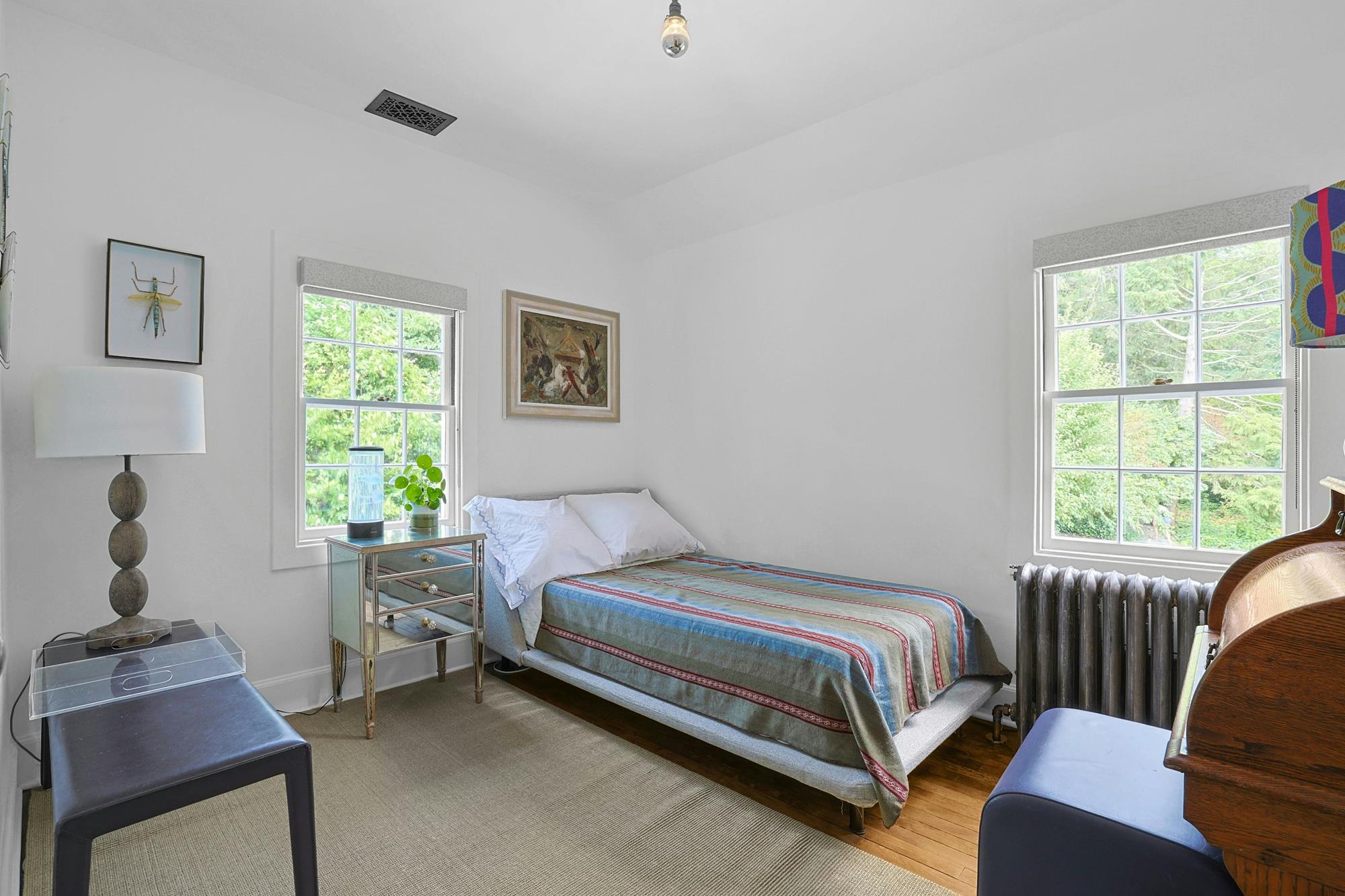 A small bedroom with a twin bed and a wide window framing the Hudson River.