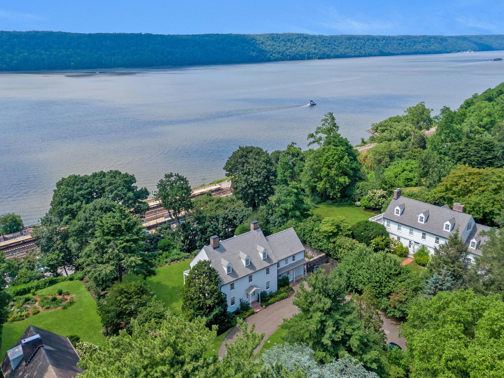 Primary bedroom with large windows framing a sweeping, majestic view of the Hudson River and the Palisades.