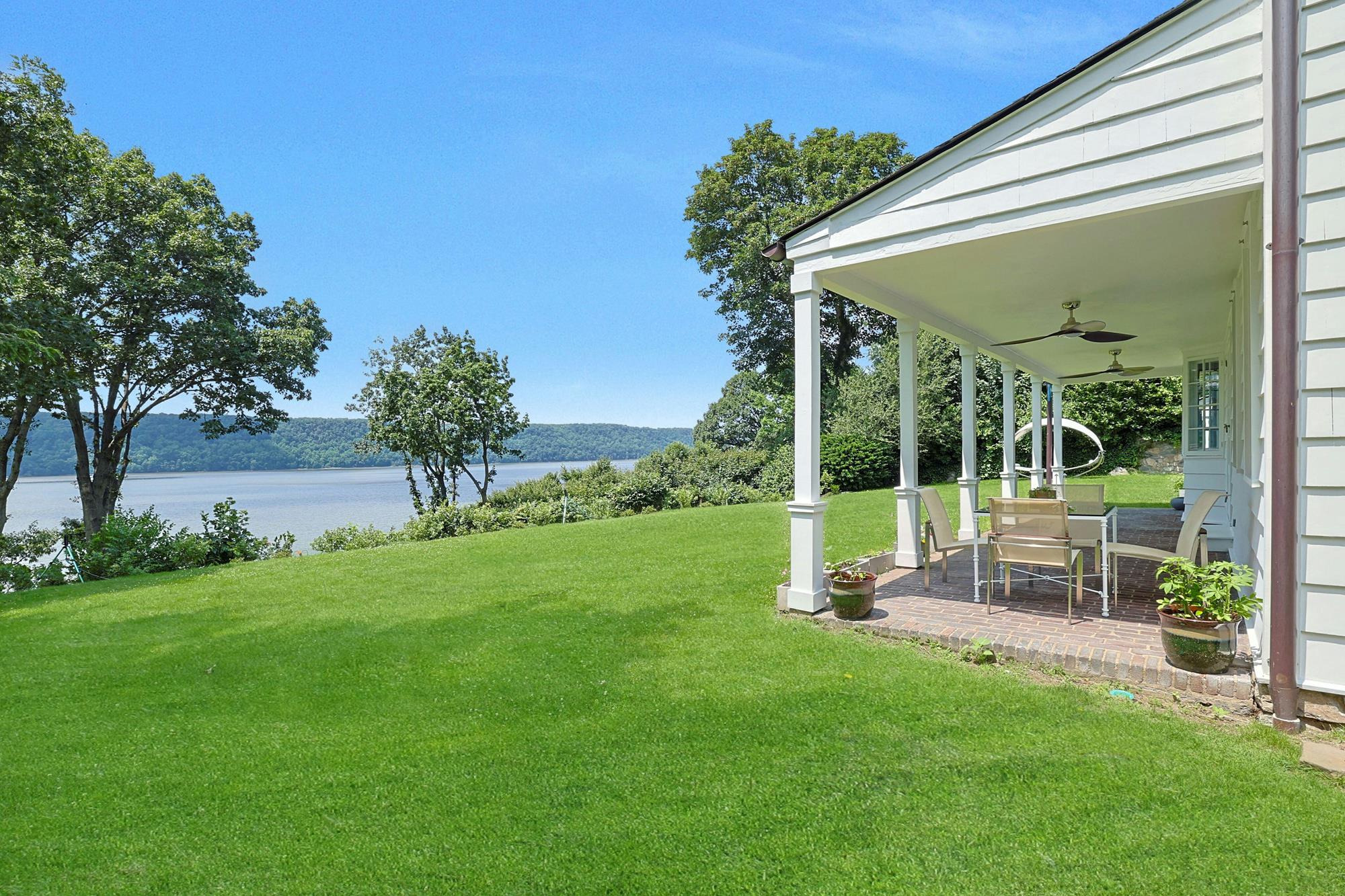 The classic columned porch opens onto a level, grassy yard above the Hudson.