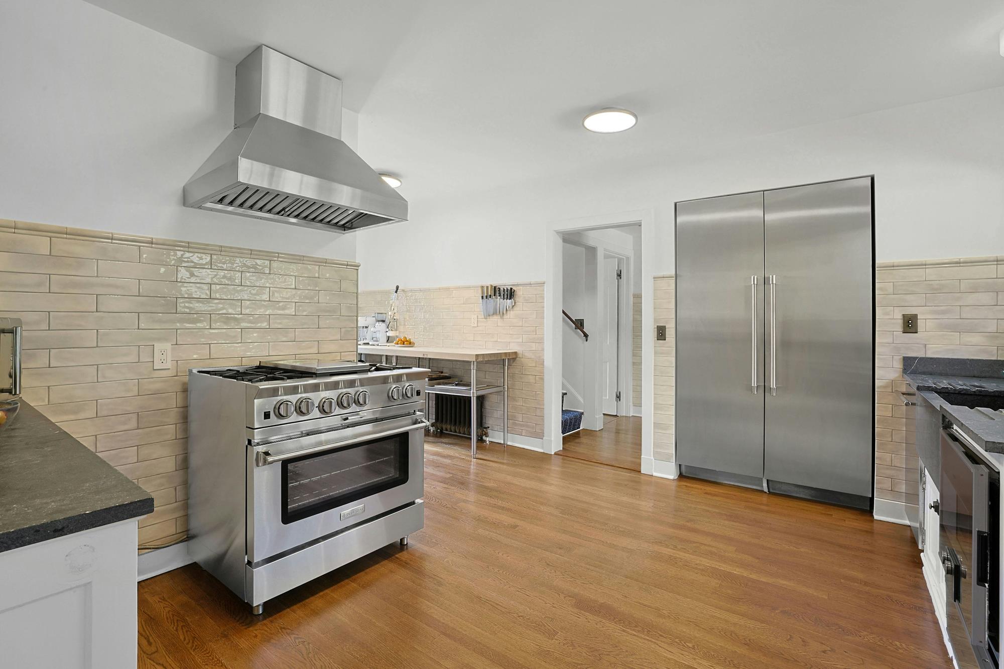 A renovated kitchen with a soapstone sink and counters, a Blue Star six-burner range, Thermador refrigerator and dishwasher, and Gaggenau steam oven and warming drawer.