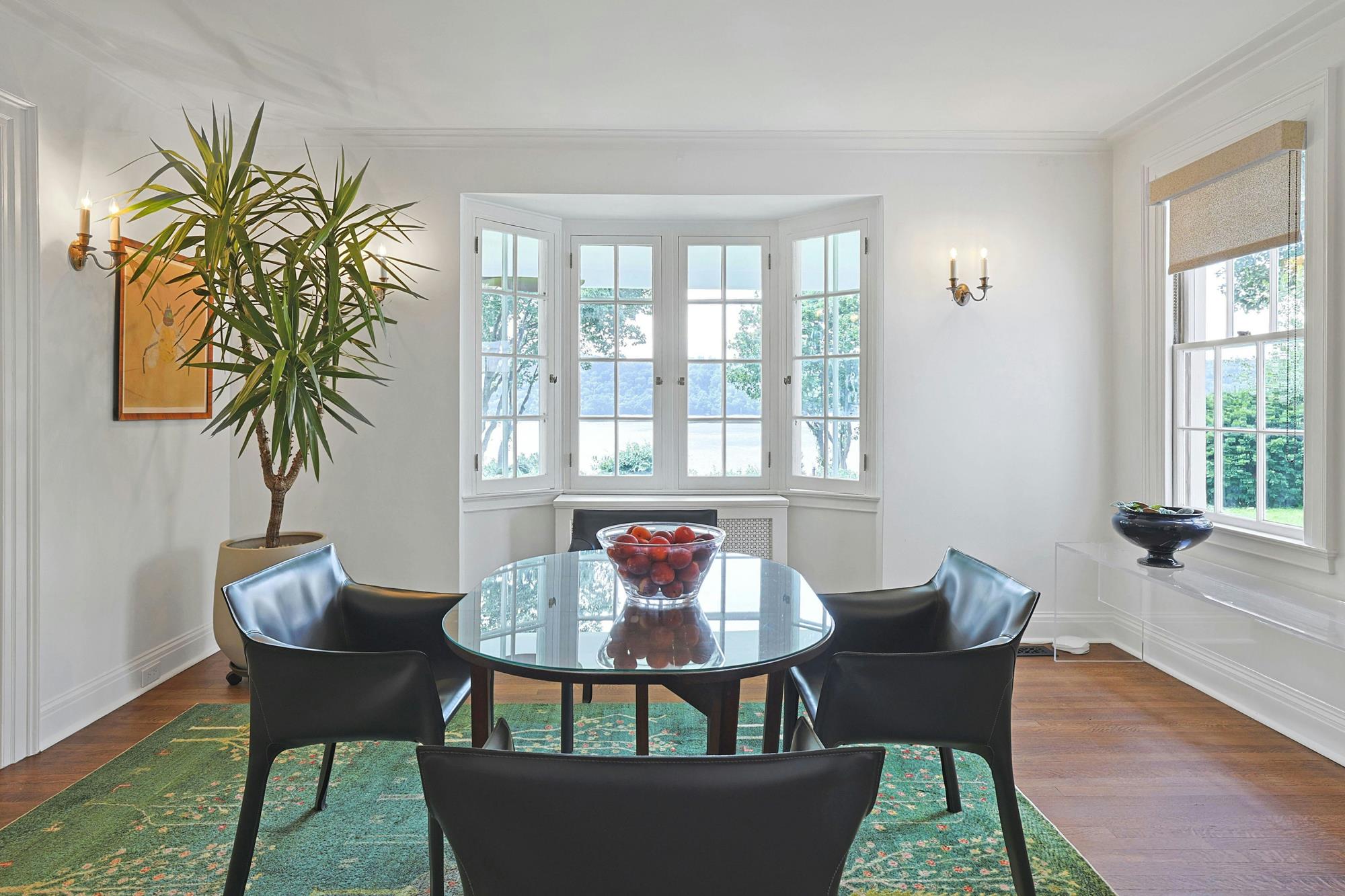 The formal dining room features a deep bay window framing panoramic views of the Hudson River and the Palisades.