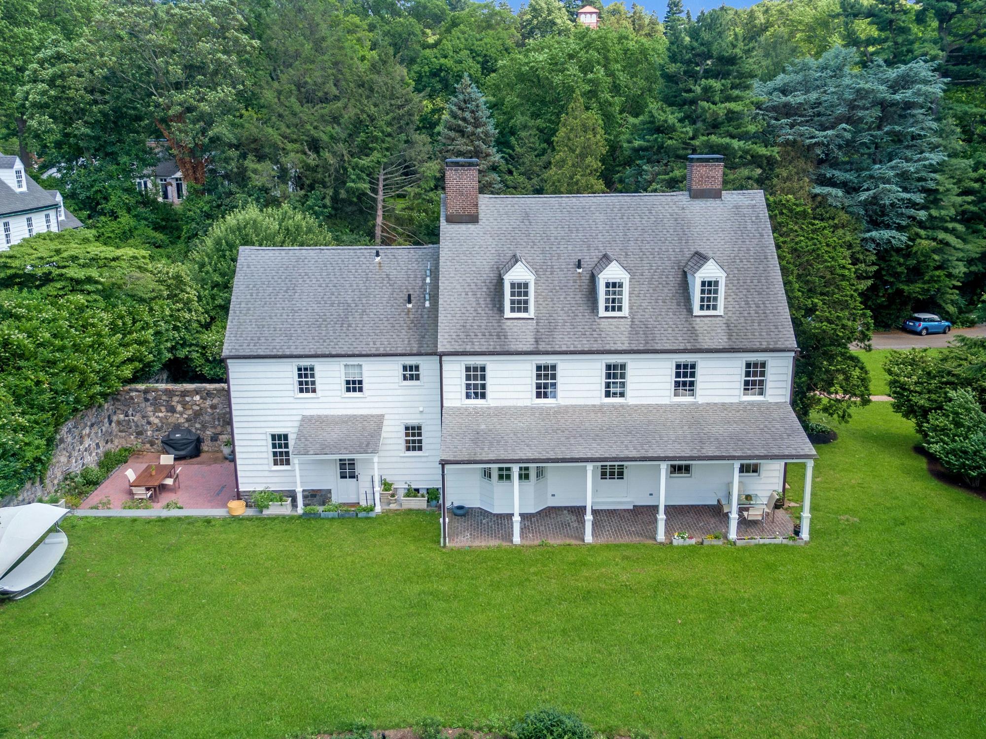 The rear elevation of the Colonial-style home showing its classic columned back porch and level lawn.